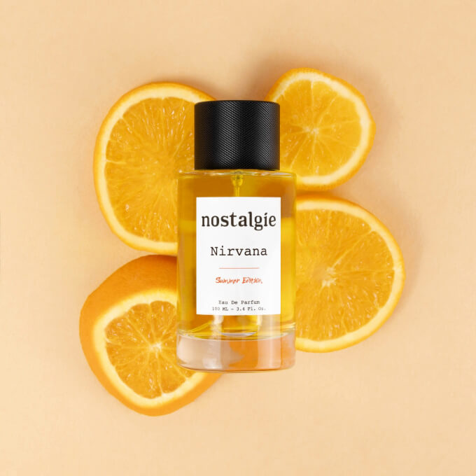 Nostalgie Nirvana perfume bottle with sliced oranges in the background.