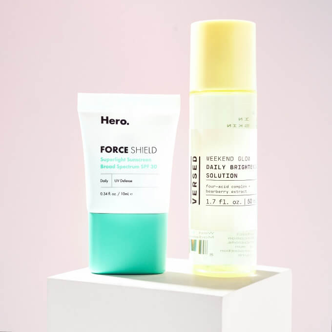 Two skincare products, Hero Force Shield sunscreen and Versed Weekend Glow brightening solution.