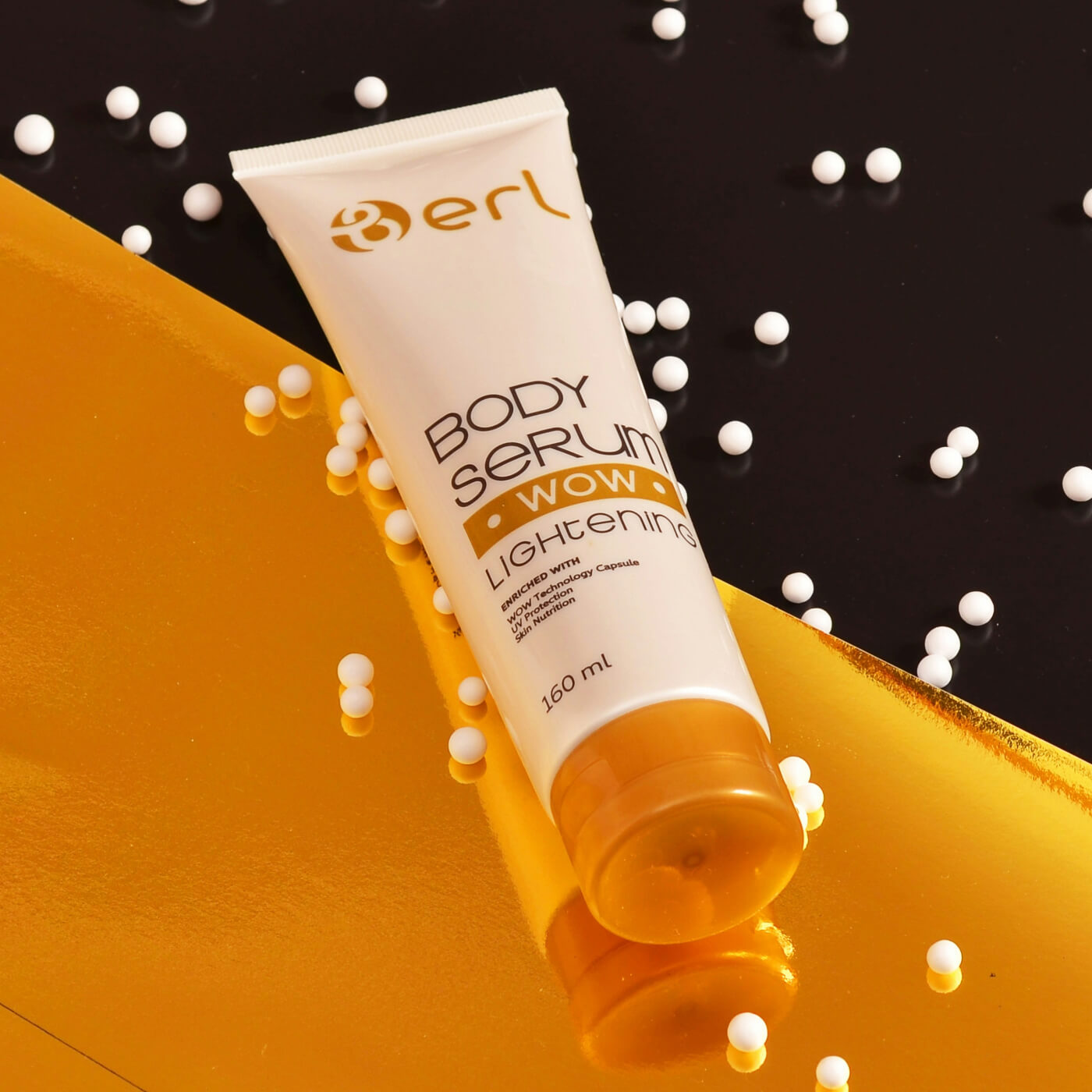 A tube of WOW body serum placed on a gold and black background with white beads scattered around.