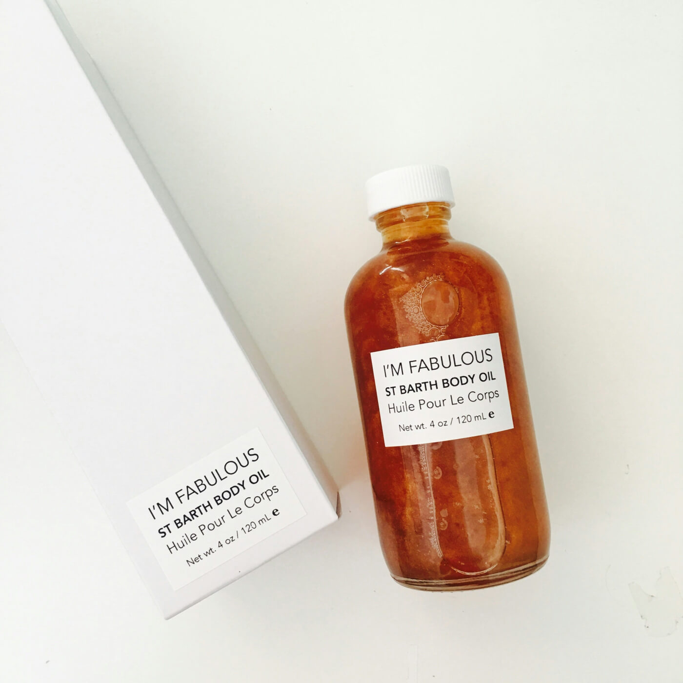 A bottle of I'm Fabulous St Barth Body Oil with its box on a white surface.