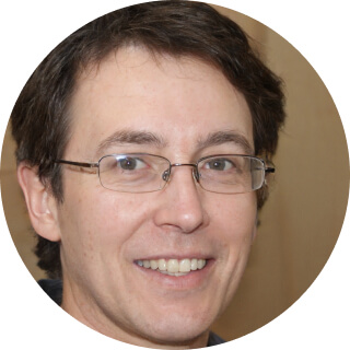 Smiling man with glasses and brown hair in close-up portrait.