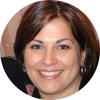 Smiling woman with brown hair and hoop earrings.