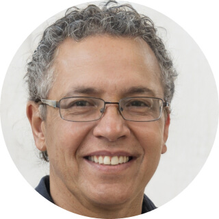 Smiling middle-aged person with glasses and curly hair.