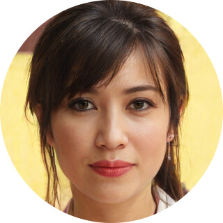 Close-up portrait of a woman with natural makeup and earrings.