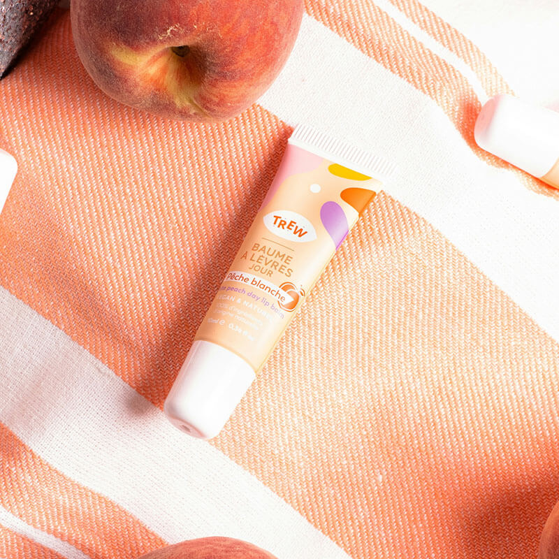 Lip balm tube on an orange and white textured fabric.