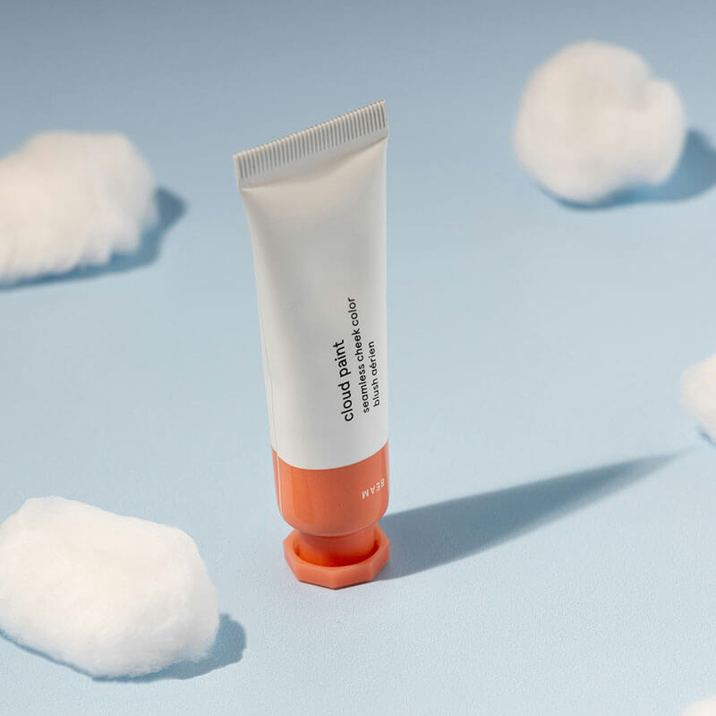 Tube of cloud paint blush with a soft blue background and cotton clouds.