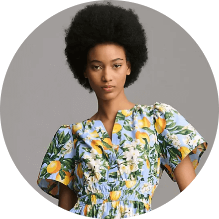 Woman wearing a floral dress with lemons and white flowers.