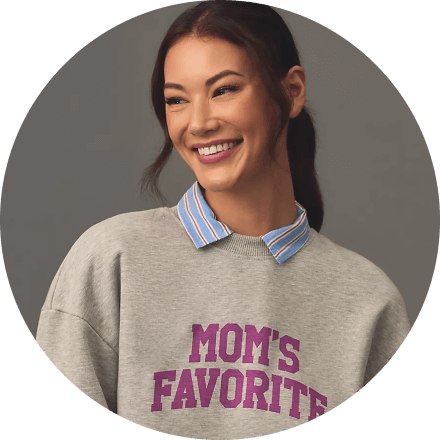 Smiling woman wearing a grey sweatshirt with text and a striped collar shirt.