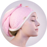 Woman wearing a pink towel turban, eyes closed, with a serene expression.