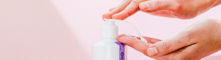 Person dispensing lotion from a pump bottle onto their finger.
